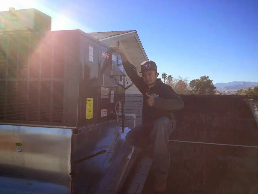 HVAC technician performing Air Duct Repair on a rooftop unit in Manassas
